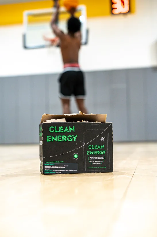 Athlete shooting a jump shot behind a Clean Energy product box